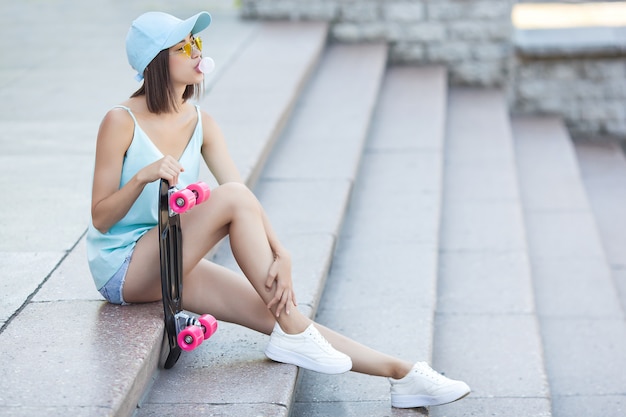 Foto skatista. mulher jovem e atraente ao ar livre, segurando o skate. mulher bonita no horário de verão.