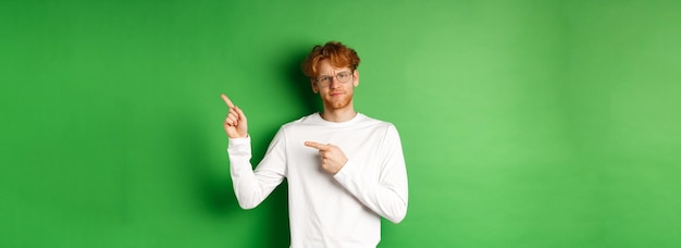 Skeptischer kaukasischer Mann mit Brille, der Zweifel hat, schmollend und die Stirn runzelnd, während er mit dem Finger nach rechts zeigt