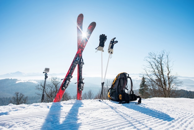 Skiausrüstung - Ski, Rucksack, Stöcke, Handschuhe und Action-Kamera auf Einbeinstativ