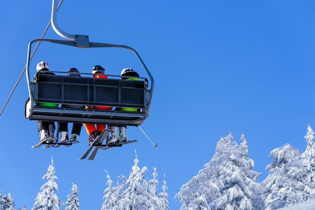 Skifahrer auf einem Skilift im Berg auf dem Hintergrund eines klaren blauen Himmels mit Kopierraum