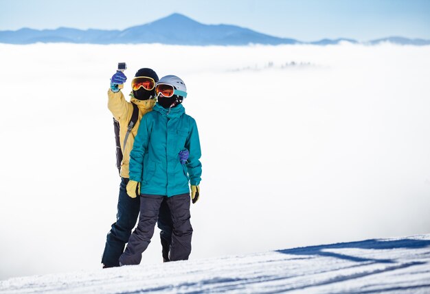 Skifahrer fotografieren sich mit dem Smartphone über einem Berg