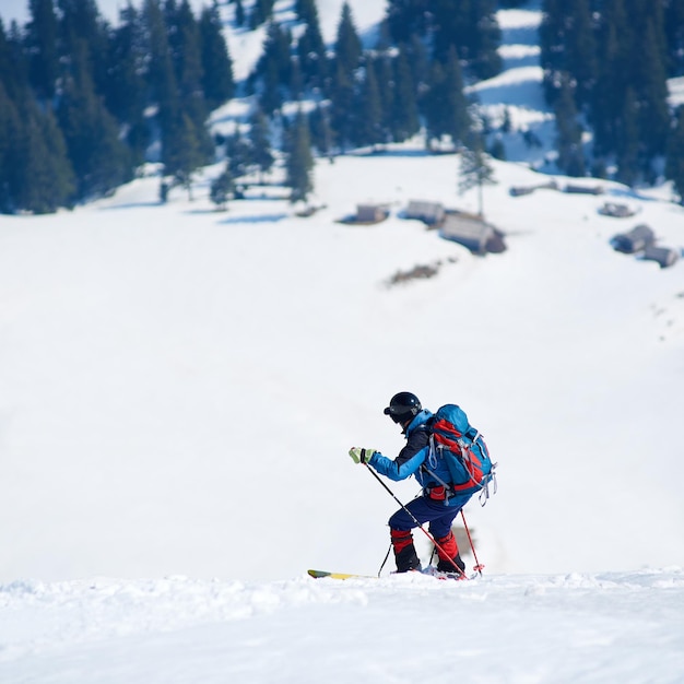 Skifahrer mit Rucksack auf Skiern im tiefen weißen Schnee vor dem Hintergrund einer wunderschönen Winterlandschaft