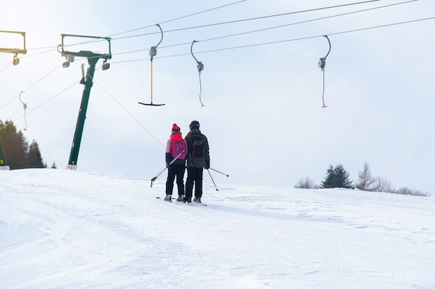 Skifahrer steigen an den Skiliften die Piste hinauf