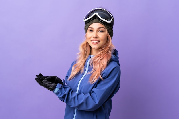 Skifahrer-Teenager-Mädchen mit Snowboardbrille über isoliertem lila Wand applaudierend