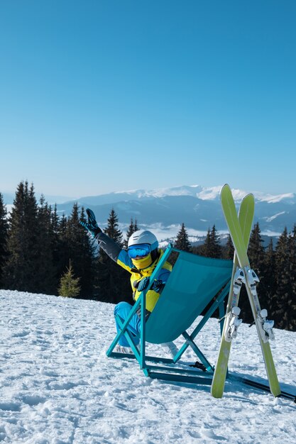 Skifahrerin, die im Stuhl mit schönem Bergpanoramablick-Skiort sitzt. Winterurlaub