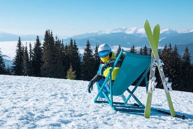 Skifahrerin, die im Stuhl mit schönem Bergpanoramablick-Skiort sitzt. Winterurlaub