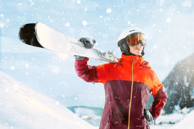 Skifahrerin, die mit Himmeln in einer Hand auf schönem Berglandschaftshintergrund steht. Winter, Ski, Schnee, Urlaub, Sport, Freizeit, Lifestyle-Konzept