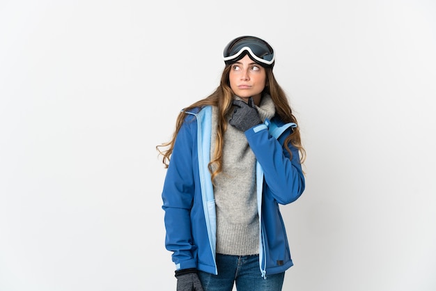 Skifahrermädchen mit Snowboardbrille auf Weiß, das Zweifel hat