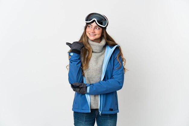 Skifahrermädchen mit Snowboardbrille lokalisiert, die zur Seite zeigt, um ein Produkt zu präsentieren