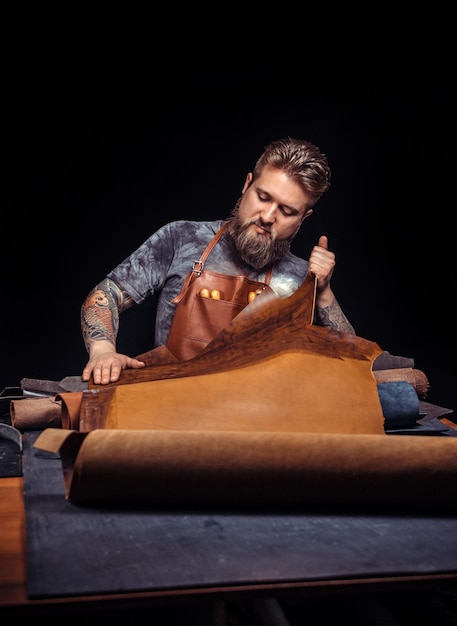 Foto skinner trabajando con cuero usando herramientas artesanales en el lugar de trabajo