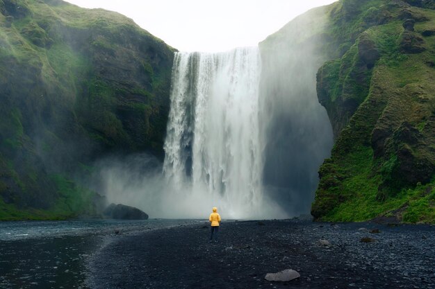 Skogafoss-Wasserfall fließt mit asiatischer Frau, die im Sommer in Island steht