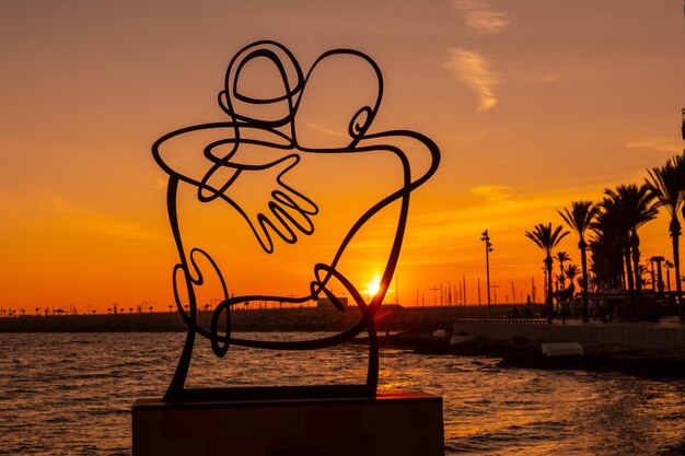 Skulptur zugunsten der Opfer von Covid im orangefarbenen Sonnenuntergang am Playa del Cura in der Küstenstadt Torrevieja Alicante Valencianische Gemeinschaft Spanien