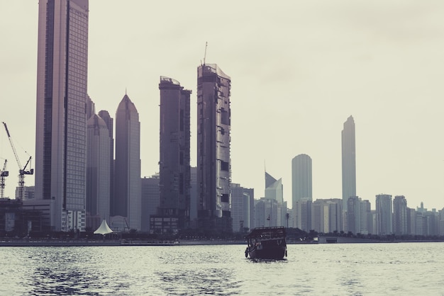 Skyline dos edifícios de Abu Dhabi com o velho barco de pesca na frente