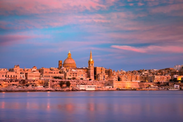 Skyline von Valletta bei schönem Sonnenuntergang von Sliema mit Kirchen Unserer Lieben Frau vom Berg Karmel und der anglikanischen Pro-Kathedrale St. Paul's, Valletta, Hauptstadt von Malta