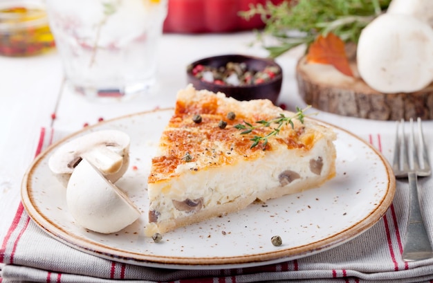 Slice de quiche de pastel de champignon de setas en un plato de cerámica sobre un fondo de madera blanca