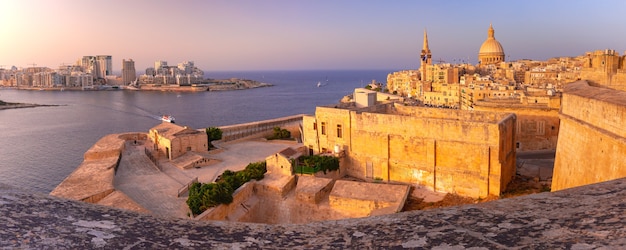 Sliema e a cidade velha de valletta com as igrejas de nossa senhora do monte carmelo e a pró-catedral anglicana de são paulo ao pôr do sol em valletta, capital de malta