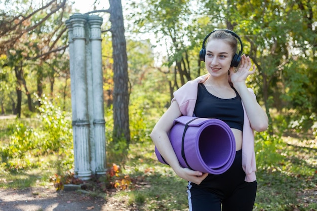 Slim Fit junge gesunde Frau mit Yogamatte in den Händen im Park Aktiver Lebensstil Outdoor-Training