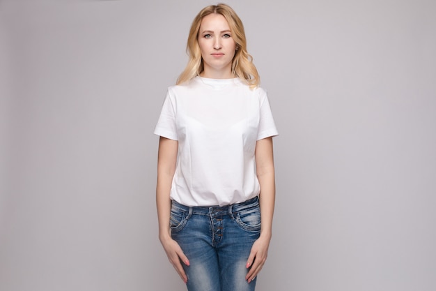 Slim mujer vestida con camisa blanca y jeans de pie estable