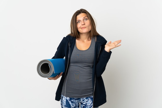 Foto slowakisches mädchen, das zu yoga-klassen lokalisiert auf weißer wand geht, die zweifel beim erhöhen der hände haben