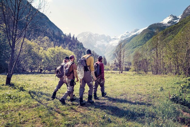 Slowenien, Bovec, vier Angler zu Fuß auf der Wiese in Richtung Fluss Soca