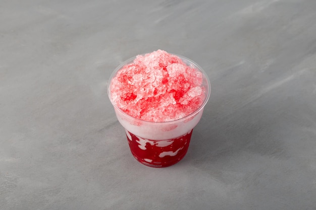 Slushie vermelho em copo plástico descartável. Gelo raspado doce. Bebida granizada de frutas espanhola.