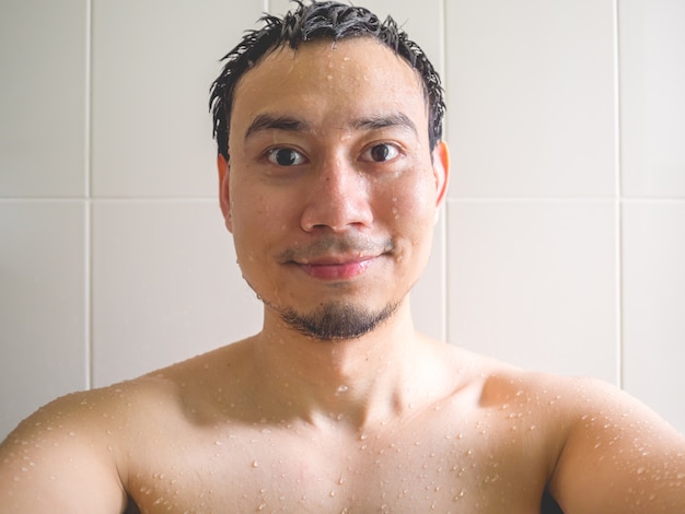 Smaile y feliz hombre asiático tomar una foto selfie en el baño mientras toma un baño