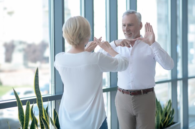 Smalltalk. Bärtiger grauhaariger Mann und blonde Frau, die Gebärdensprache sprechen