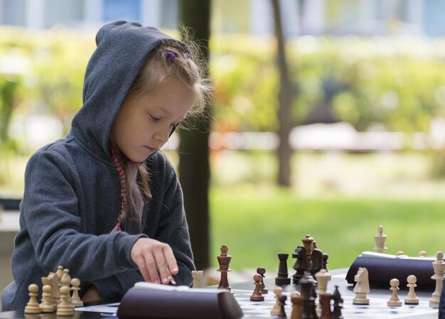 Smart Girl, de siete años, participa en un torneo de ajedrez para niños al aire libre en el parque
