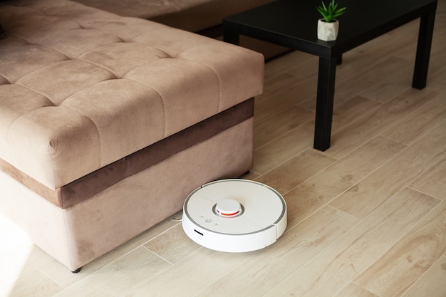 Smart House, el robot aspirador funciona en un piso de madera en una sala de estar,