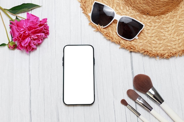 Smartphone-Attrappe auf sommerlichem Hintergrund mit Pfingstrosen und Strohhut im Urlaub