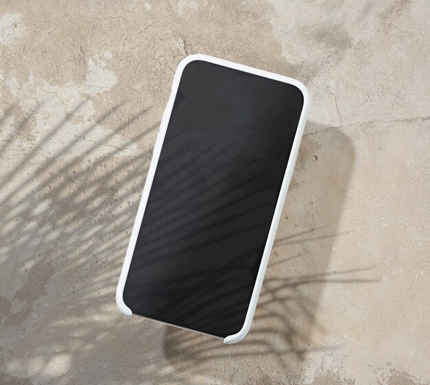 Smartphone auf beigefarbener Tischplatte mit Palmblattschatten, Draufsicht