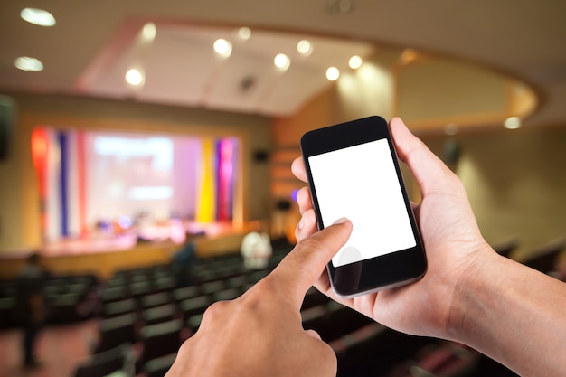 Smartphone auf der Hand und weißen Bildschirm mit verschwommenen Hintergrund des Theaters.