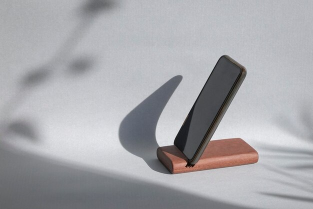 Smartphone auf einem Haltermodell mit Schatten auf Wandhintergrund