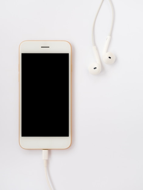 Foto smartphone, auriculares y cable de carga en blanco