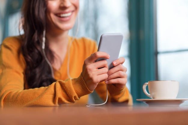 Smartphone avançado. Close up de concurso jovem feminino mão segura telefone enquanto xícara de chá está na superfície