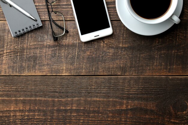 Smartphone blanco y anteojos con una taza de café