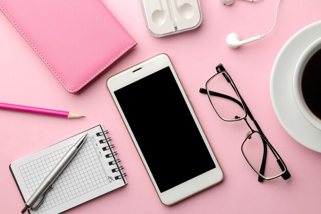 Smartphone blanco y auriculares con una taza de café