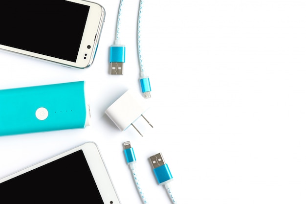 Smartphone blanco con banco de baterías y cables de carga usb en vista superior