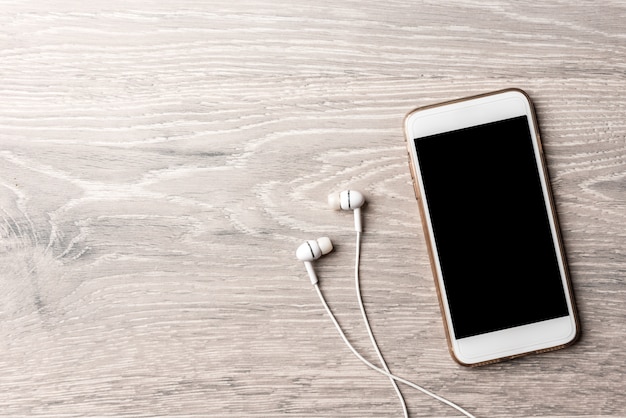 Smartphone blanco con un cuaderno sobre una mesa de madera