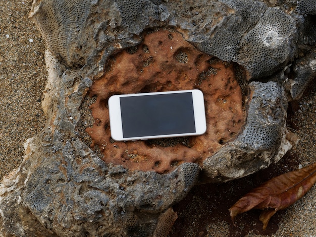Smartphone blanco sobre una roca marrón