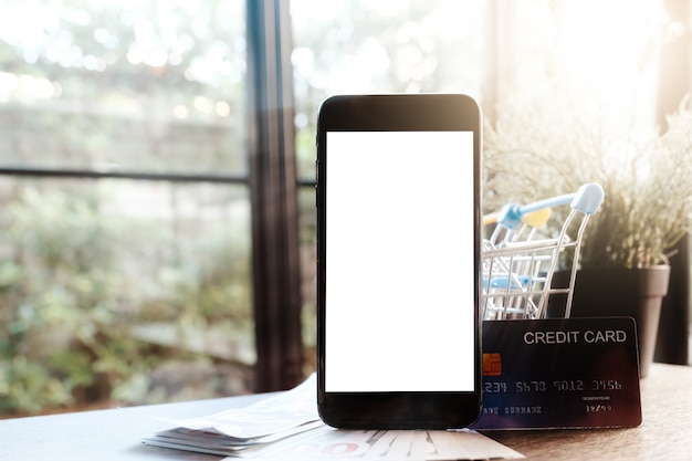 Smartphone en blanco con tarjeta de crédito y dinero en la mesa