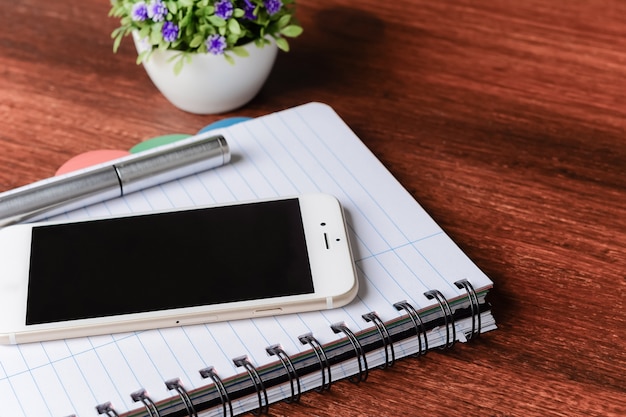 Foto smartphone con bolígrafo sobre cuaderno en blanco