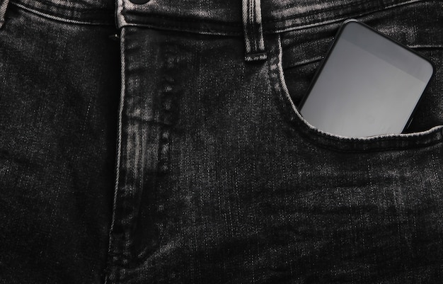 Smartphone en el bolsillo delantero de jeans negros