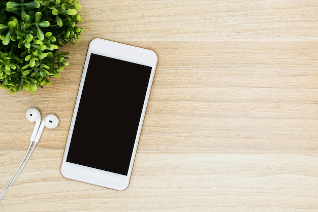 Smartphone branco com tela em branco é na mesa de madeira.