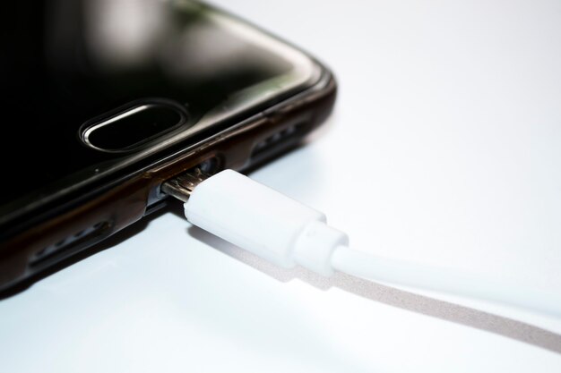 Foto smartphone con cargador sobre fondo blanco cable usb