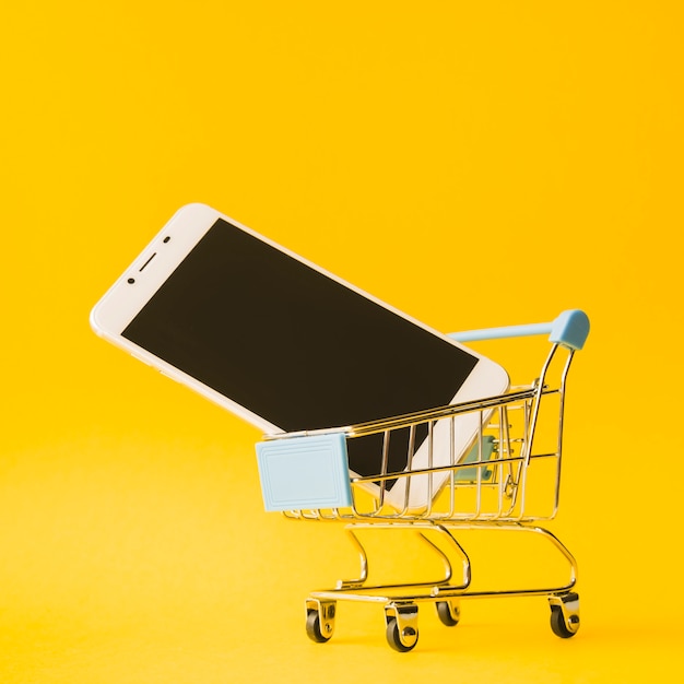 Foto smartphone en carrito de supermercado de juguete