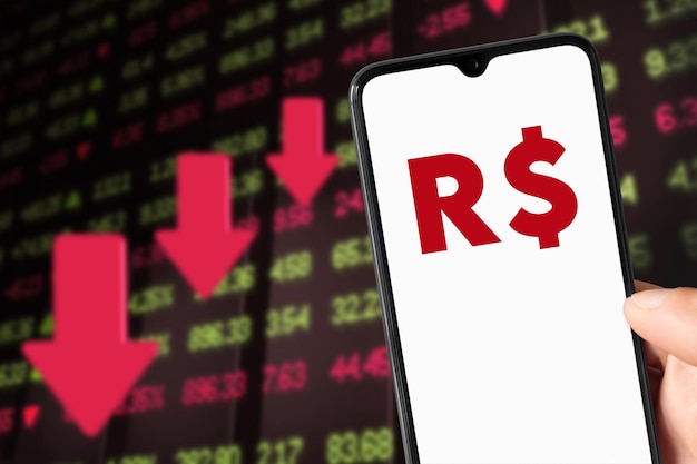 Smartphone com símbolo Real R e fundo mostrando a queda do valor de mercado 24 de maio de 2022 São Paulo Brasil
