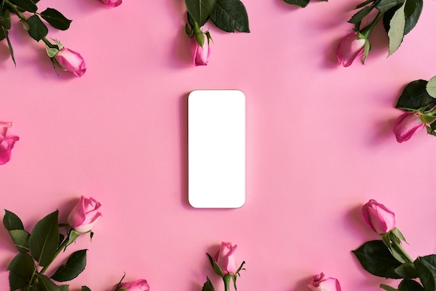 Smartphone com tela branca em branco no fundo rosa com flores rosas