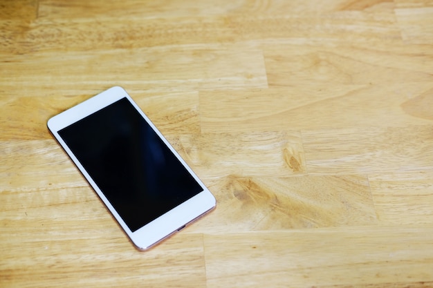 Smartphone com tela branca na mesa de madeira.