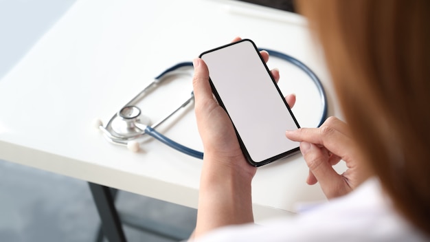 Smartphone com tela em branco na mão do médico feminino